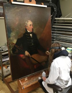 A conservator conducts tests on the portrait of Thomas Pinckney in a studio
