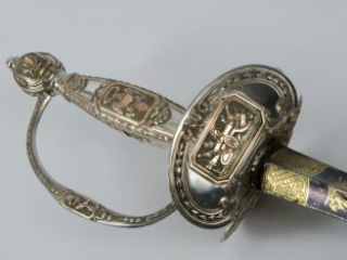 Angled detail of a silver and gold presentation sword hilt