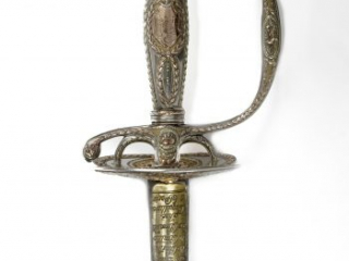 Vertical detail of the silver and gold hilt of a presentation sword