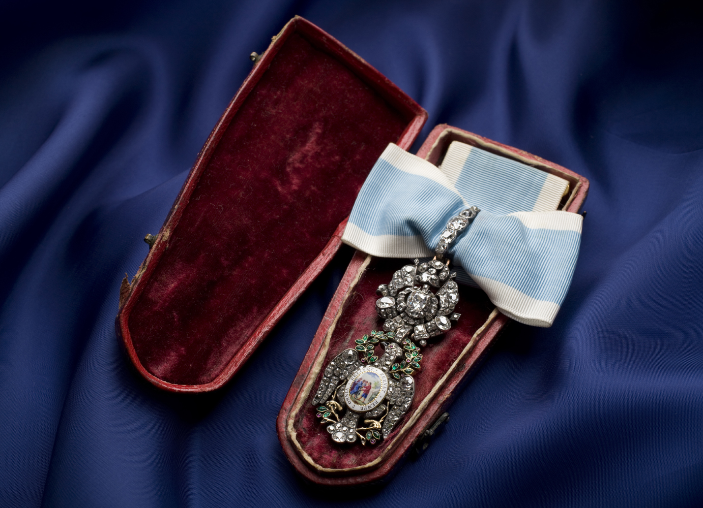 Bejeweled insignia resting inside a red velvet-lined case
