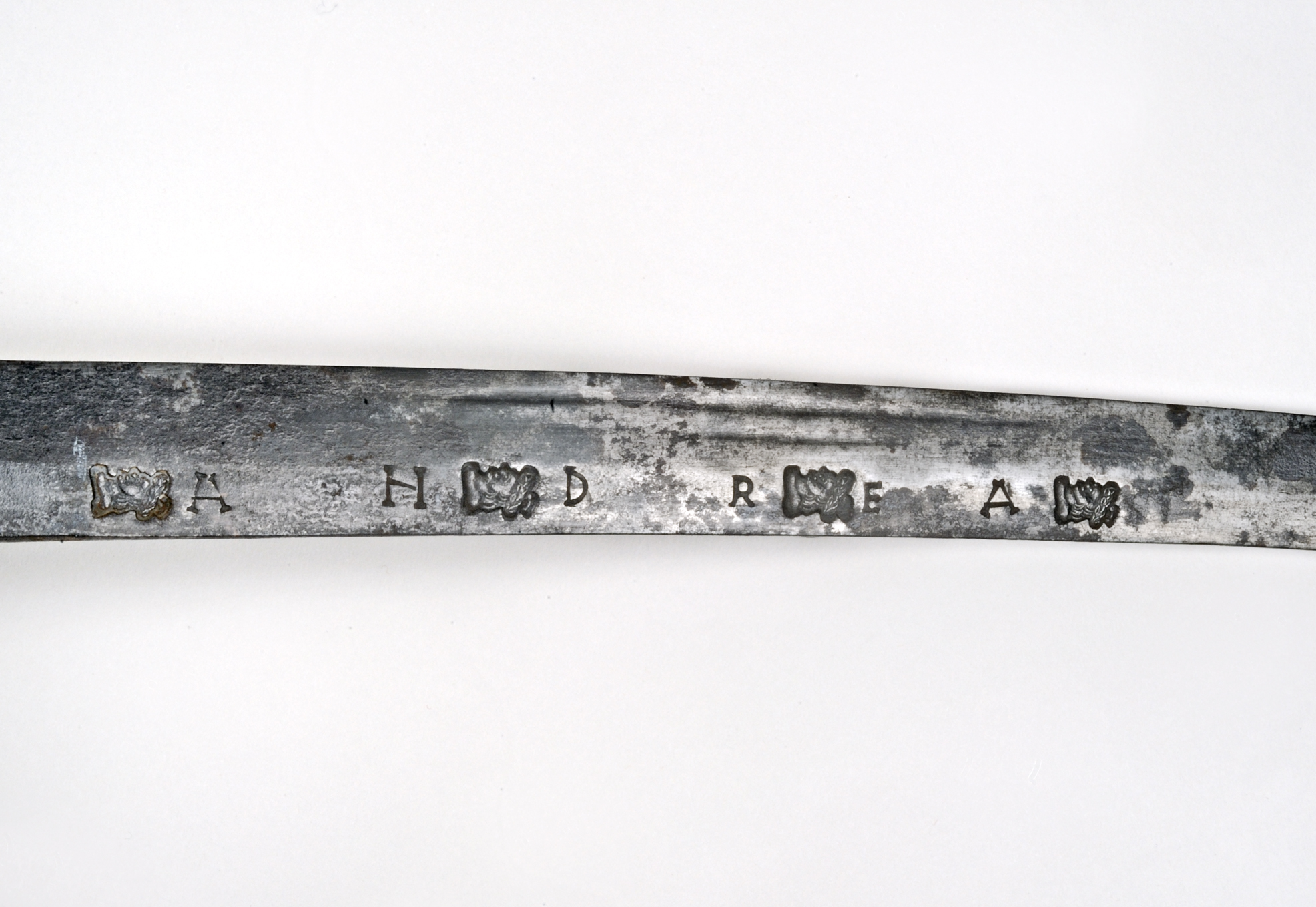 Detail of a slightly curved sword blade showing stamped letters and marks