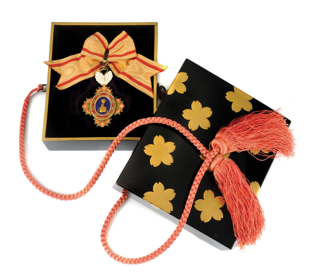 Orange and blue medal with an orange and red ribbon in a black and gold box with red cords