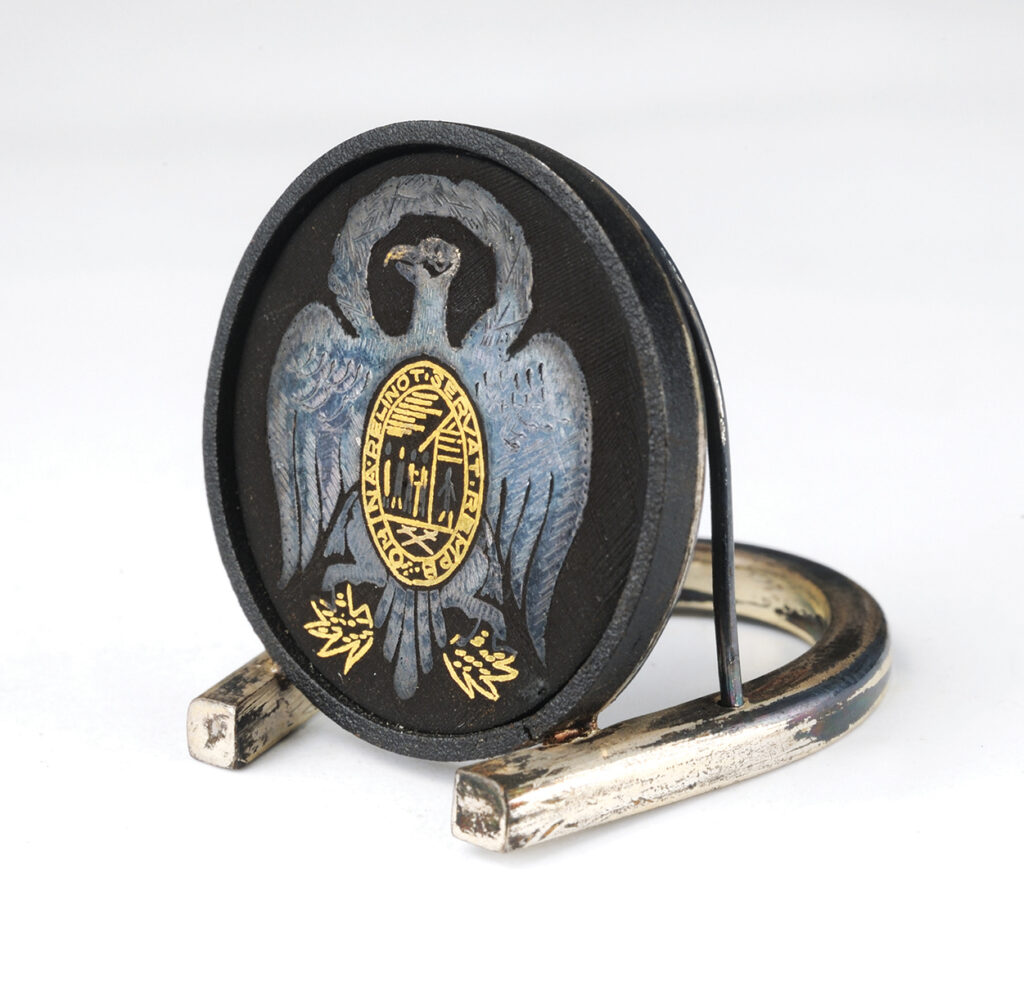 Black circular place card holder bearing a silver and gold image of an eagle