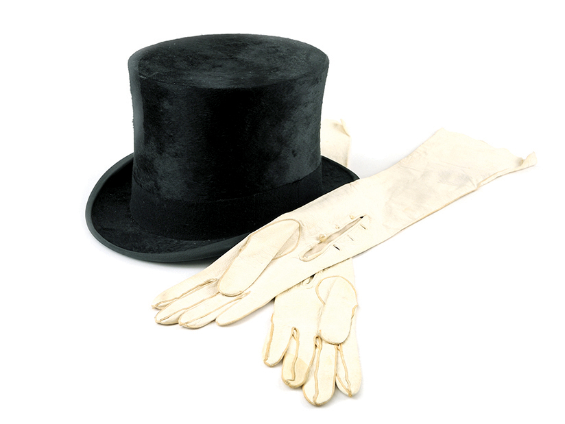 Black top hat next to white opera gloves crossed