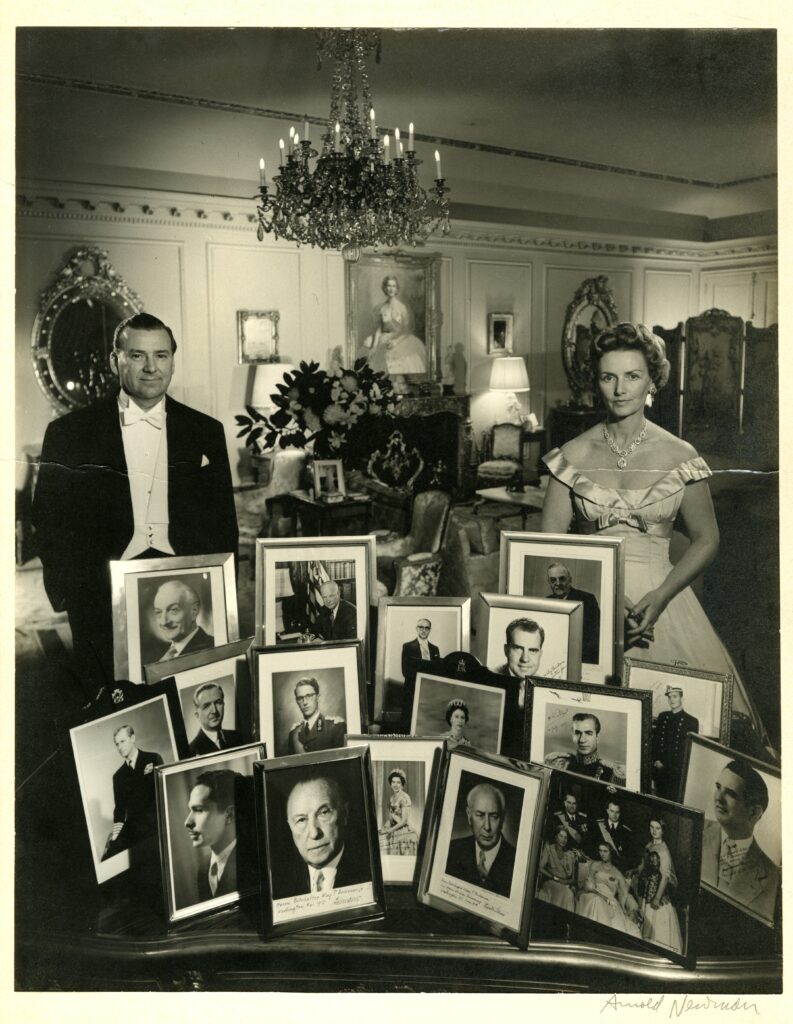 Black-and-white photograph of a couple in formal dress standing behind framed portraits of world leaders